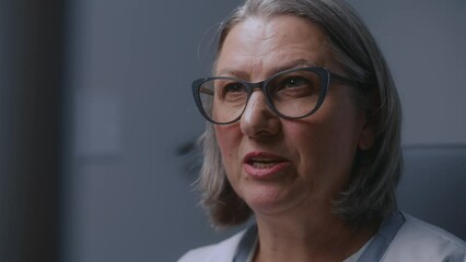 Close up shot of professional female doctor looking at monitor of sonography machine while doing ultrasound diagnostics. Medical specialist conducts check up or examination in modern clinic. Portrait.