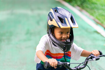 Fototapeta na wymiar Kindergarten boy practice ride bicycle in city park