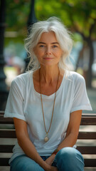 Obraz premium Old Caucasian woman sitting on bench on background of green summer city park.