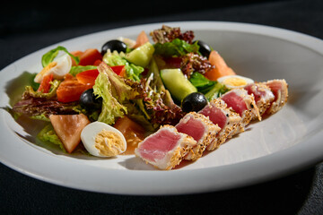 Close-up of Niçoise salad with medium seared tuna on a white plate
