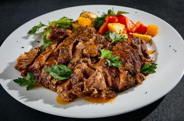 Close-up of beef brisket with roasted vegetables on a white plate