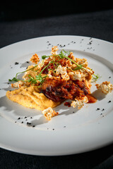 Savory beef medallions with vegetable puree on a textured black surface, a closeup of fine cuisine