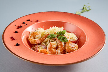 Seafood pasta with succulent shrimp, served in a rustic red plate, ideal for Mediterranean cuisine promotion and food magazines