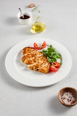 Golden crusted chicken fillet with cheese on a bed of lettuce, topped with cherry tomatoes, ideal for recipes and menu designs