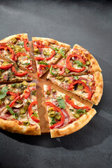 Meat lovers' pizza with bacon, ham, marinated pickles, and paprika, bursting with flavors and toppings