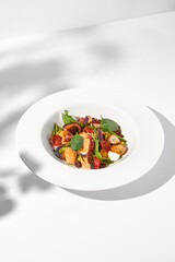 Mediterranean salad with octopus, potatoes, tomatoes, and Kalamata olives in a spicy sauce, shadowed on a white background