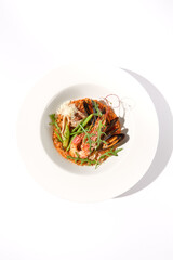 Top view of tomato risotto with seafood on white, suitable for Mediterranean diet and seafood cuisine showcases