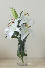 Beautiful lilies flowers in a vase on the table, pastel tones.