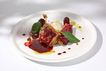 Confit duck leg with berry sauce casting a soft shadow on white, a luxurious and flavorful fine dining experience