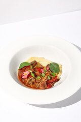 Braised beef with vegetables and mushrooms served with mashed potatoes, on an isolated white background, a hearty meal