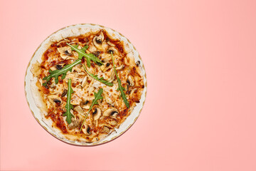 Top view of gluten-free pizza with mushrooms and tomatoes, served on a chic plate over a pink background