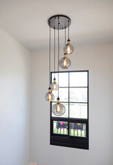 Modern pendant lamp hanging in home staircase by the window.