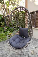 Rattan wicker cocoon garden swing chair hanged on frame. Recreation scene with a hammock-chair in the backyard of the house. Relax concept with hammock chair .