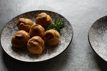 Profiteroles with custard, on beautiful plates, close-up