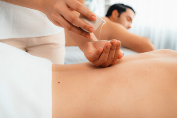 Masseur hands pouring aroma oil on couple's back. Masseuse prepare oil massage procedure for customer at spa salon in luxury resort. Aroma oil body massage therapy concept. Quiescent