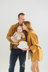 Parents celebrating their birthday with their little son. The concept of family holidays. Young parents congratulate their son on his birthday with a cake.