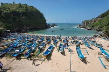 Fototapeta na wymiar Blue fishing boats anchored on the shore. White sandy beach with blue turquoise crystal sea water. 