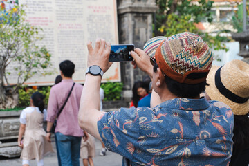 Naklejka premium Asian man take a photo with smartphone on street.