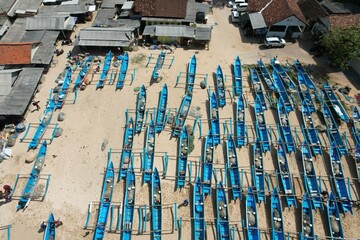 aerial photography of white sandy tropical beach with blue fishing boats lined up neatly on the...