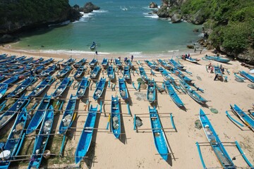 Fototapeta premium aerial view of white sandy beach in tropical island. people enjoying vacation in tropics. blue fishing boat by the beach.
