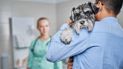 Owner holding his dog at the veterinarian