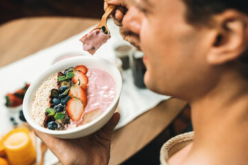 Focused photo on healthy food yogurt toppings with berry fruit in smart broadcaster tasting blurred face, promoting with advertisement online for benefit of vitamin and fiber each meal. Pecuniary.