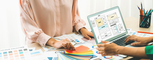 Cropped image of interior designer chooses color from color swatches while laptop displayed website...
