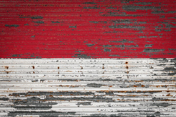 Close-up of old metal wall with national flag of Monaco . Concept of  Monaco export-import, storage of goods and national delivery of goods. Flag in grunge style