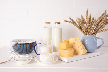 Fresh homemade dairy products for the holiday of Jewish Shavuot on a white wooden table. Front...