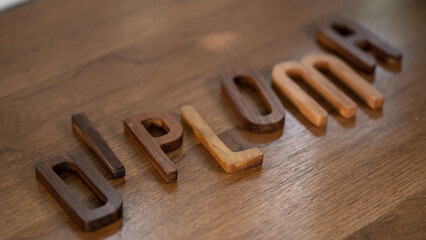 Artisanal Décor: 3D Walnut 'Diploma' Letters Adorn Wooden Table