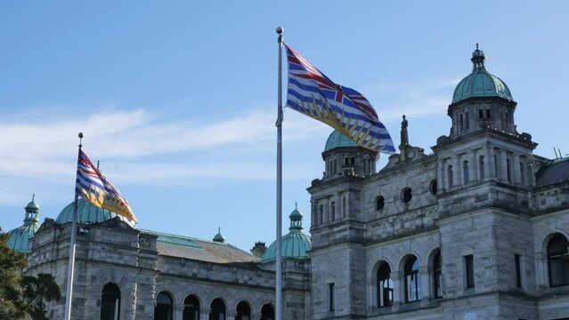 Flags of British Columbia waving in front of the Legislative Assembly of British Columbia Parliament Building in Victoria on Vancouver Island in Canada