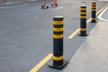 black steel bollards with yellow reflective tape on ground floor. steel bollards traffic equipments.