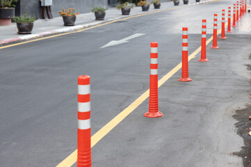 plastic bollards with white reflective tape on ground floor. orange bollards traffic equipments.
