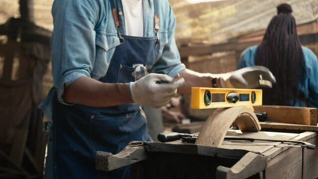 Handsome craftsman skillfully use Precision Bubble Level on a piece of wood , Carpenter is doing a business making a wooden furniture in a wood shop