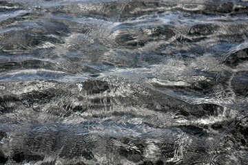 View of clear water with a slight rough sea. Small waves on the sea on a sunny day. Seabed in shallow waters in calm conditions.