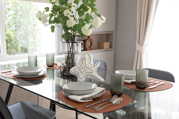 White and brown plate setting on dinning table with flowers vase in a dining room