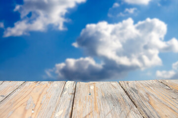 photo of a wooden board with a blue sky and clouds in the background