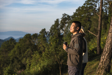 Asian man having cup of morning coffee enjoy forest and mountain atmosphere
