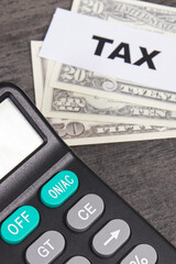Calculator, inscription tax and dollar banknotes. Calculating and paying tax