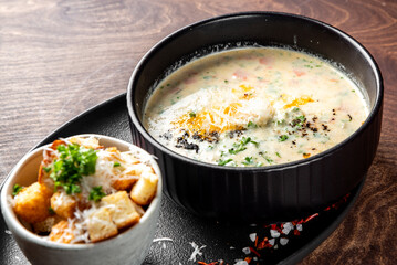 Salmon soup with cream, potatoes, carrots and parsley on wooden background