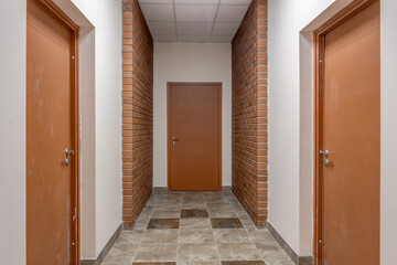white empty long corridor with red brick walls in interior of modern apartments, office or clinic.
