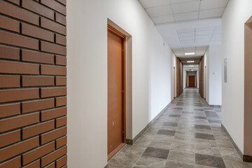 white empty long corridor with red brick walls in interior of modern apartments, office or clinic.