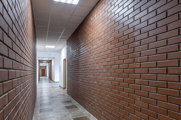 white empty long corridor with red brick walls in interior of modern apartments, office or clinic.