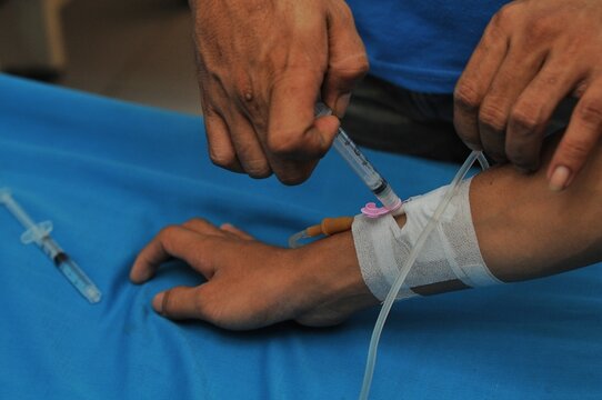 a paramedic's hand injects medication into a patient who is being given an IV drip
