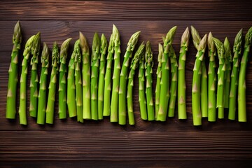 bunches of fresh green asparagus arranged in a row individually on a daily brown background, top view