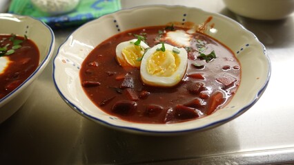 Homemade winter soup with tomatoes, beetroot, cream eggs and parsley.