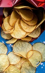 Fresh potato chips in an open package on a blue background.