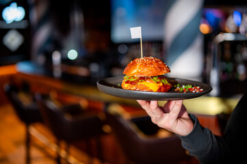 waiter holding plate with burger at cafe