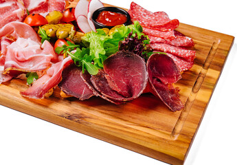 Variety of meats, sausages, salami, ham, olives, laid out on a wooden board