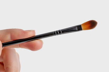 Hand holding make-up brush cosmetic isolated on gray